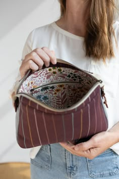 a woman is holding a purse in her hand and looking down at the inside of it