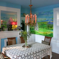 a dining room with a table and chairs in front of a painting on the wall