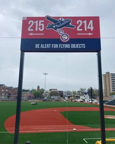 a baseball field with a sign that says, be alert for flying objects on it