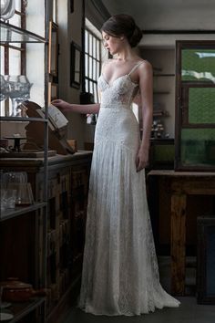 a woman in a white wedding dress looking at something on the shelf next to her