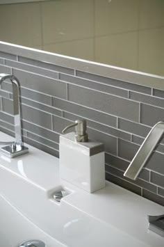 a white sink sitting under a mirror next to a faucet and soap dispenser