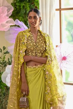 Shine bright like a diamond at this season’s soirees. The lime green set comes with a blouse covered with daisy flower applique work. The dhoti-style skirt also glamourizes the outfit with its asymmetrical look. The Dupatta/cape that is paired with the outfit has an ombre effect to tie in all the colors of the embellishments. Blouse comes with a V-neck along with hook in the front accentuated with daisy intricacies all over. A ombre cape made out of cutwork at the border entices the outfit. Drap Pista Green Saree Blouse For Party, Green Zari Work Blouse For Party Wear, Green Zari Work Party Wear Blouse, Elegant Pista Green Blouse Piece For Party, Elegant Pista Green Blouse For Party, Pista Green Georgette Blouse For Party, Green Traditional Wear With Unstitched Blouse For Party, Green Traditional Drape Blouse For Party, Party Blouse In Pista Green Georgette