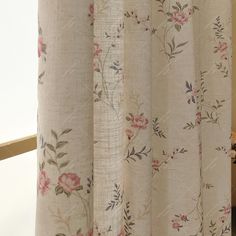 a close up of a shower curtain with flowers on it and a vase in the background