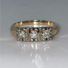 three stone diamond ring in yellow gold and white gold with diamonds on each side,