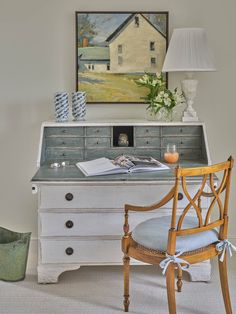 a desk with a chair, lamp and painting on the wall