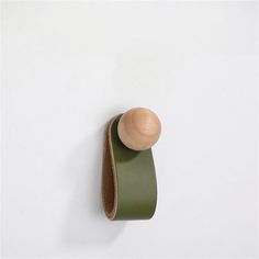 a wooden object hanging on the wall next to a roll of green tape and a wood spoon