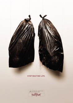 two black bags hanging from strings in front of a white wall with the words stop wasteing life written on it