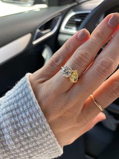 a woman's hand holding onto the steering wheel of a car while wearing an engagement ring