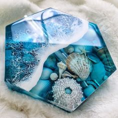 a blue glass plate with shells and seaweed on it sitting on a white furnishing