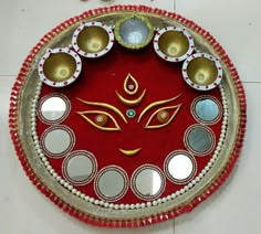 a red and gold decorated plate with mirrors on the bottom, surrounded by silver circles