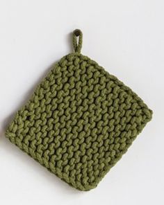 a green crocheted pot holder on a white surface