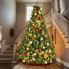 a decorated christmas tree in the corner of a room with stairs and banisters