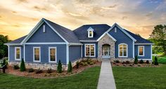 a blue house with white trim on the front and side windows is shown at sunset