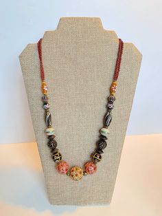 Stunning Handmade Dayak (Borneo) Beads Necklace. Hand painted beads with different color tone.  The unique and meticulous patterns inscribe on each bead. Hailing all the way from the island of Kalimantan in Indonesia, these beads are carefully handcrafted using the finest materials including carnelian, crystal, clay and other natural stone.  In the same way each stroke of red, yellow and blue paint depicts the unequivocal talents of the craftsman. Orange Bohemian Hand-strung Beaded Necklace, Traditional Czech Glass Beaded Necklaces, Traditional Necklace With Polished Czech Glass Beads, Traditional Czech Glass Necklace With Polished Beads, Multicolor Wooden Beads Oval Necklaces, Multicolor Wooden Oval Beads Necklace, Multicolor Oval Wooden Beads Necklace, Multicolor Necklace With Oval Wooden Beads, Traditional Czech Glass Large Beads