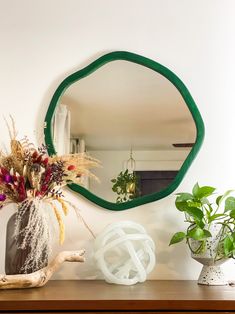 a mirror sitting on top of a wooden table next to a vase filled with flowers