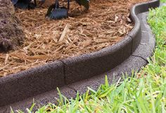 a close up view of the edge of a garden bed with grass and mulch