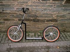 an orange and black scooter is parked next to a brick wall