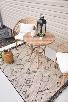 two wicker chairs sitting on top of a rug next to a table and chair