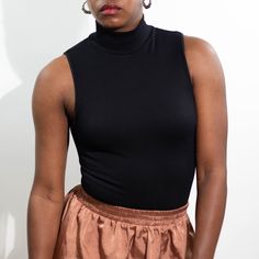 Layer her up or bare your arms. A simple staple with a little bit of texture. Sleeveless ribbed seamless top in black. 92% Nylon 8% Spandex One-Size Chic Ribbed Turtleneck Tank Top, Stretch Mock Neck Top For Night Out, Fitted Sleeveless Black Mock Neck Top, Black Fitted Sleeveless Mock Neck Top, Stretch Mock Neck Top For Evening, Stretch High Neck Turtleneck For Night Out, Chic Solid Color Sleeveless Mock Neck Top, Trendy Ribbed Turtleneck Tank Top, Chic Sleeveless Mock Neck Top In Solid Color