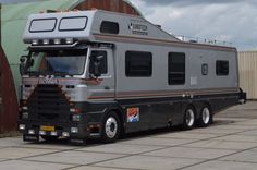 a large gray truck parked in front of a building with an awning on it's roof