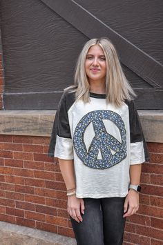 Spread peace and love wherever you go with our Peace Sign Patch Top, a symbol of harmony and unity that never goes out of style. Crafted from soft, breathable fabric, this top combines comfort with a timeless message of positivity. The standout feature of this top is the vibrant peace sign patch adorning the front, adding a pop of color and personality to your ensemble. Whether you're a free spirit, a peace activist, or simply appreciate the power of a meaningful symbol, this top is sure to reso Hippie Crew Neck Soft-washed Top, Hippie Soft-washed Crew Neck Top, Soft-washed Hippie Crew Neck Top, Hippie Soft-washed Relaxed Fit Tops, Hippie Style Soft-washed Relaxed Fit Top, White Hippie Tops With Letter Print, Hippie Letter Print Tops For Spring, Spring Leisure Graphic Tee Tops, Comfortable Relaxed Fit Tops For Leisure