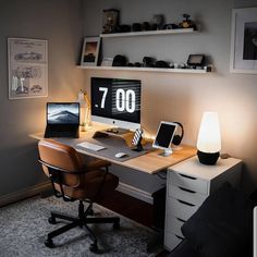 a desk with a computer, lamp and phone on it in a room that is lit up