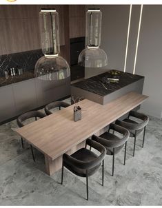 a dining room table with six chairs and two pendant lights above it, in front of a kitchen counter