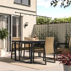 an outdoor dining area with patio furniture and potted plants on the side of the house