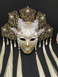 Venetian Mask for decoration - Traditional and original papier-mache Venetian mask, handmade and decorated with metal insert, gold-leaf and glitters, enriched with Swarovski crystals. Dimension::Hight 35cm,width 28cm Decoration only,not wereable All our masks are handmade paper-machè masks made in Venice. Our decorators use techniques typical of the Venetian tradition such as stucco, acrylics, gold and silver-leaf, macramè, passementerie, glitters and crequelè to offer you a wide range of origin Traditional White Mask For Carnival, Gold Fantasy Headpiece For Carnival, Traditional White Masks For Carnival, Traditional White Carnival Mask, Gold Headpieces For Costume Party And Carnival, Venetian Gold Mask For Party, Gold Venetian Mask For Party, Gold Venetian Masks For Party, Gold Venetian Party Mask