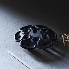 several black buttons sitting on top of a table next to two knitting needles and an object