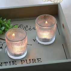 two glass candles sitting on top of a tray