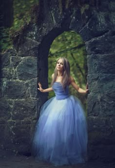 a woman wearing a blue dress standing in an archway