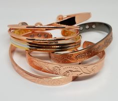 6 different styles of copper bracelets. Main picture, top to bottom: Plain, 2 wire, multicoloured, leaves, floral vine, and roses.  Wearing copper bracelets for medicinal benefits has a long history, all the way back to ancient Egypt. Proposed benefits focus on reducing joint inflammation and easing pain. Researchers attribute the benefits of copper bracelets to the absorption of trace minerals into the bloodstream. Microminerals of iron and zinc, present in the copper, combine with sweat on the Traditional Adjustable Rose Gold Bracelets, Cells And Tissues, Crystal Holder, Body Tissues, Medical Bracelet, Cuff Bangle Bracelet, Copper Cuff, Magnetic Bracelet, Copper Bracelet