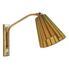 a wall light with a striped shade on the lamp is shown in gold and green