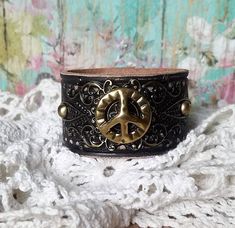 "v'¯) .`*.¸.*' ★ Leather cuff bracelet, always with a FeMiNinE flair ❤ This DESIGN ~ ❤ This gold peace sign concho and exquisite filigree, enhanced with a bit of black patina, sit on tooled leather that was hand painted black. Distressed to show all the details. Width of leather is approximately 1 1/2\". BRACELET SIZING INFO: My women's bracelets are approximately 8 1/2 inches end to end. I place 2 snaps at 7 and 7 3/4 inches for adjustability. jewelry for your heart & soul <-----❤----" Vintage Adjustable Cuff Bracelet, Vintage Adjustable Cuff Bracelet As Fashion Accessory, Vintage Adjustable Cuff Wristband, Vintage Handmade Adjustable Wristband, Handmade Adjustable Vintage Wristband, Handmade Vintage Adjustable Wristband, Vintage Leather Cuff Bracelet For Festival, Adjustable Vintage Wristband, Peace Sign Jewelry