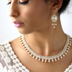 a woman wearing a necklace and earrings with pearls