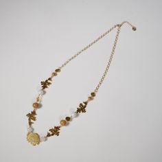 a gold necklace with leaves and beads