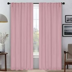 a living room with pink curtains and pictures on the wall