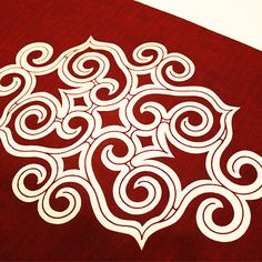 a red table cloth with white swirls on the top and bottom, along with an intricately designed design