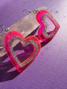 > hot pink and glitter acrylic heart shaped earrings are perfect for valentine's day or your next y2k look > a gift that sparkles * they would make a wonderful gift for someone who likes unique handmade jewelry * > the cut out hearts are laser engraved 1/8th inch thick acrylic with sterling silver ear wires > they are hypo-allergenic and nickel free  > the acrylic hearts are 1.75 inches wide and 1.72 inches long with a drop length of .5 inches  > feel free to message me if you would like to request a custom size > check my other listings for many other color options such as purple and iridescent  > find me on instagram @queen.beams for a firsthand look at how my items are made <3 Pink Glitter Heart Earrings For Party, Pink Glitter Earrings For Valentine's Day, Pink Glitter Jewelry For Valentine's Day, Valentine's Day Pink Glitter Earrings, Valentine's Day Pink Glitter Jewelry, Valentine's Day Party Heart Earrings With Open Heart Shape, Pink Heart Charm Earrings For Valentine's Day, Pink Heart Cut Earrings With Heart Charm, Trendy Pink Double Heart Earrings