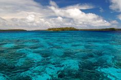 the water is crystal blue and clear with some small islands in the distance on an island