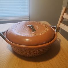 a brown casserole sitting on top of a wooden table next to a window