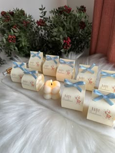 small candles are sitting on a white furnishing with blue bows and tags attached to them