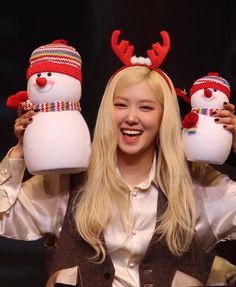 a woman holding two snowmen wearing reindeer hats