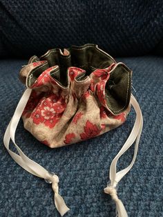 a small purse sitting on top of a blue couch next to a white ribbon tied around it