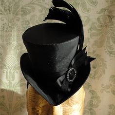 This gothic victorian mini top hat is an excellent choice for any dark cabaret event. It is covered with taffeta and embellished with various black trimmings. Two curled black rooster feathers, ribbons, a silver and black rhinestone round buckle and a just a hint of black veil. Choose between total black(pictured),blue or burgundy with black decoration. Measurements : height 4 inches( 10 cm ) front to back 9 inches ( 22 cm ) side to side 7.5 inches ( 19 cm ) This mini top hat is fully lined with Victorian Witch, Raven Wings, Elizabethan Collar, Ruff Collar, Ladies Hat, Mini Top Hat, Cocktail Hat, Victorian Steampunk, Black Pins