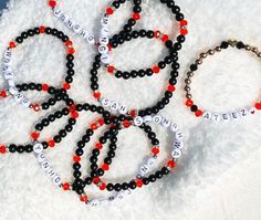 six bracelets with black and red beads on white furnishing, including one bead