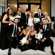 a group of people in suits and ties posing for a photo with their bouquets