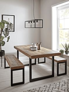 a dining room table with two benches and a potted plant in the corner next to it