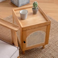 a small wooden table with a potted cactus on it and a chair next to it